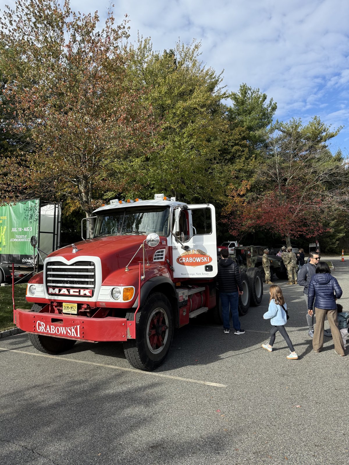 Mack truck with a crowd and a uniformed first responder in frame.
