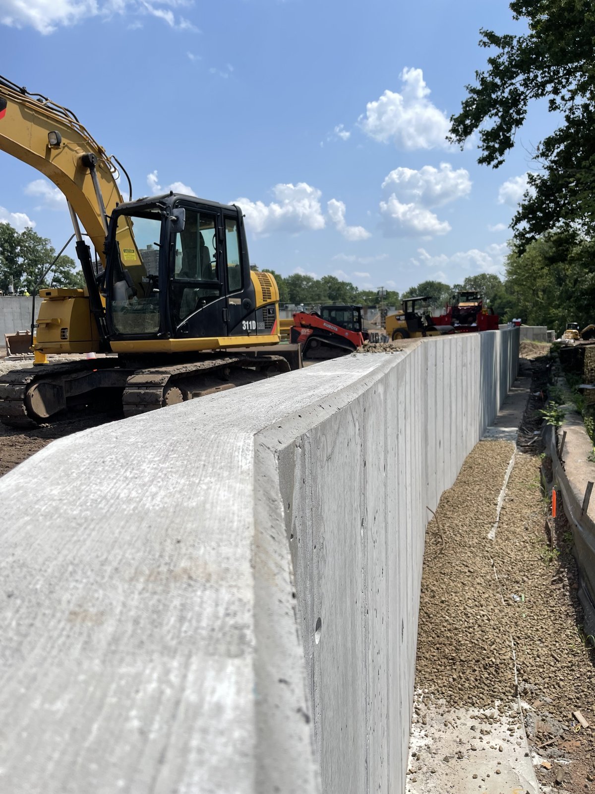 CAT 319D excavator working alongside the completed board-form retaining wall.