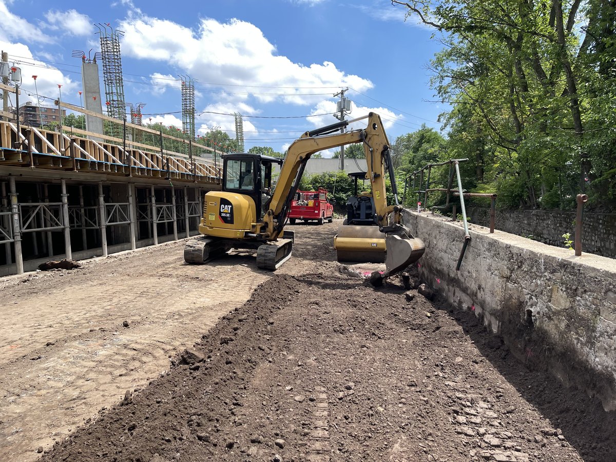 CAT mini-excavator working next to the board-form retaining wall during install.