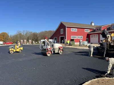 Asphalt rolling against the red-barn facade at Express Auto Spa.