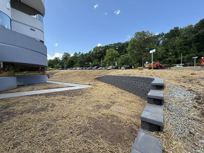 Segmental block retaining wall and stone drainage swale curving along the Marotta Controls building.
