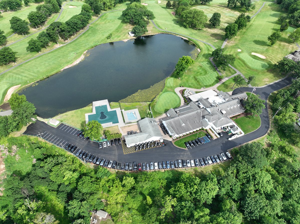 Aerial over the pond of the newly paved parking lot wrapping along the hillside behind the Rock Spring clubhouse.