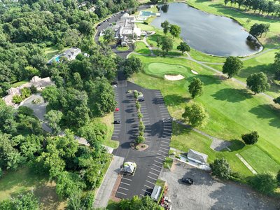 Aerial of the paved and striped lower parking lot with landscaped islands beside the golf course.