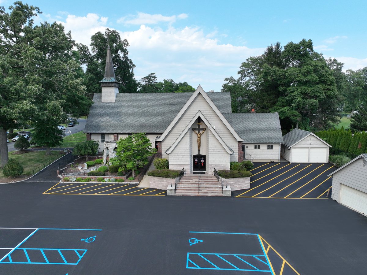 Freshly paved and striped parking lot in front of St. Joseph's Roman Catholic Church, with blue ADA stalls and yellow hatched zones.
