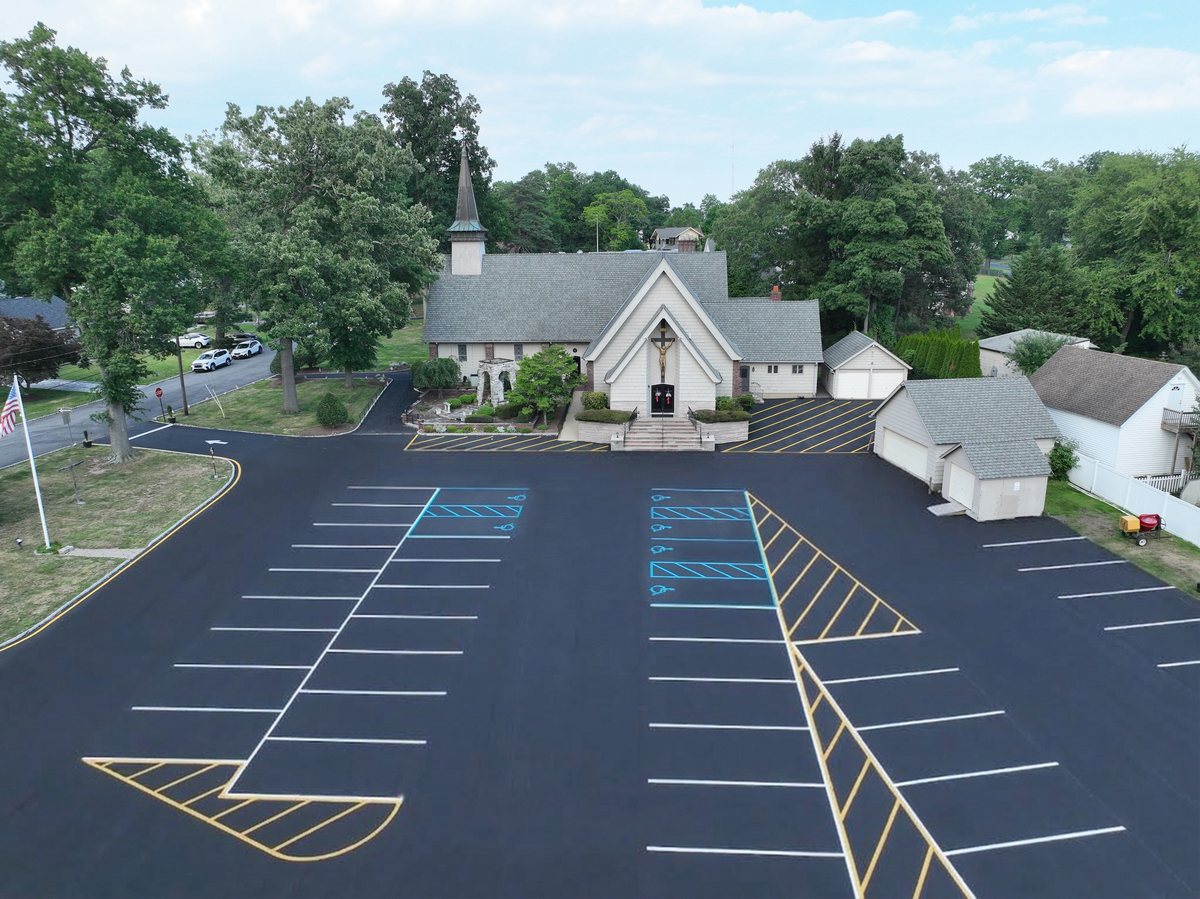 Wider drone view of St. Joseph's church and steeple over the newly milled and paved parking lot.