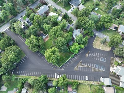 Overhead aerial of the full St. Joseph's parking lot after mill and pave, with fresh white, yellow, and blue striping.
