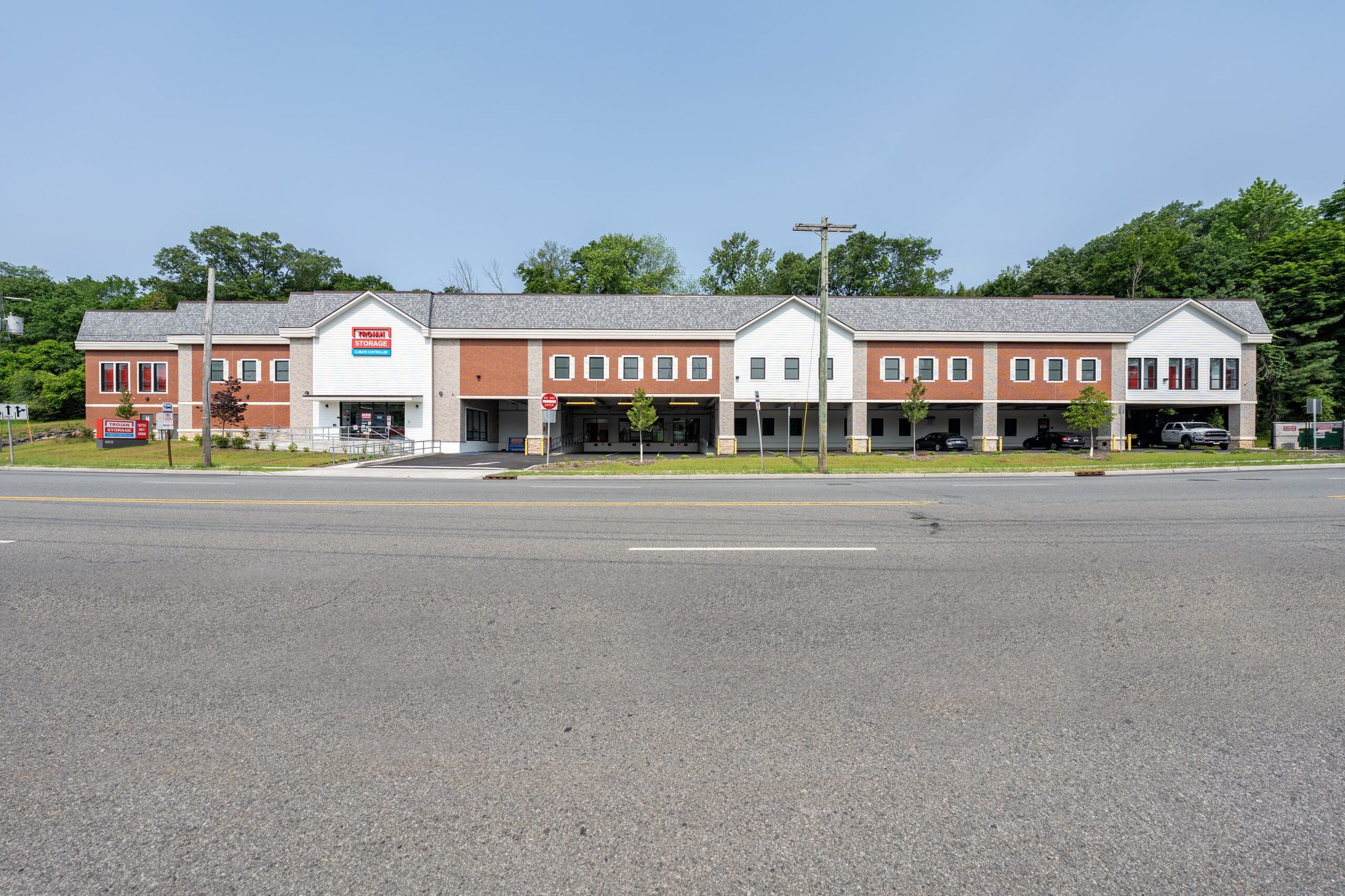 Asphalt paving in progress along the finished red-brick facade of Trojan Storage West Orange.