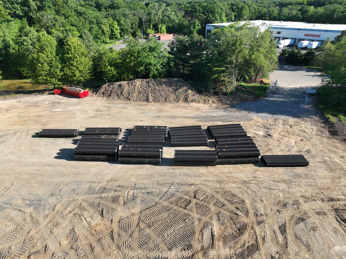 Stockpiled black HDPE drainage pipe staged on site ahead of underground utility installation.