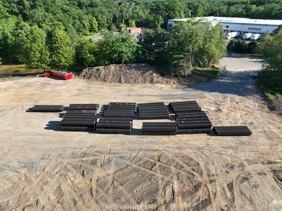 Stockpiled black HDPE drainage pipe staged on site ahead of underground utility installation.