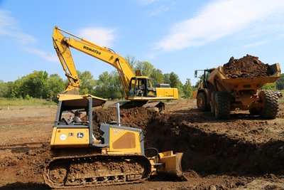 Komatsu PC400LC excavator loads articulated dump truck while John Deere 450J dozer grades