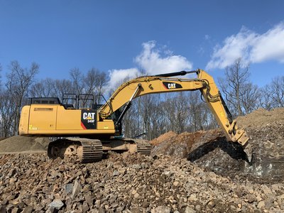 Cat 349F excavator perched on a rock cut bench under a clear blue sky