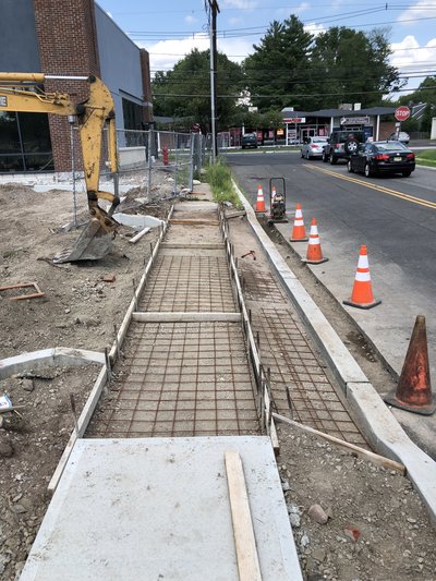 Wire mesh reinforcement laid in formed sidewalk bed before concrete pour beside roadway