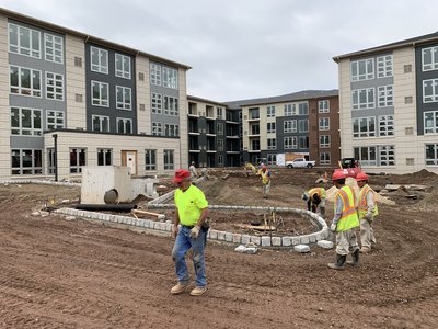 Crew installs curved cobblestone curbing for a landscaped island between residential buildings