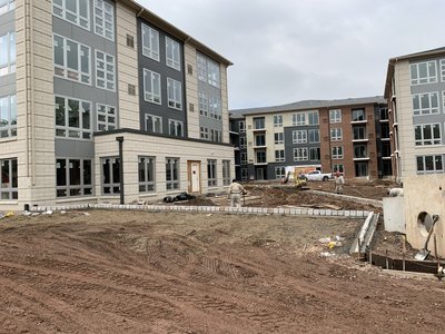 Long stretch of cobblestone curbing installed across a graded site beside multistory buildings