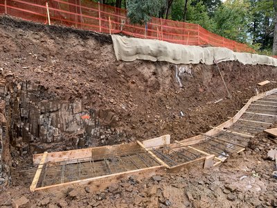 Steel rebar grid in wooden formwork prepared for a retaining wall against a slope