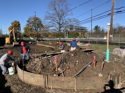 Crew works inside curved formwork with rebar for a circular retaining wall foundation