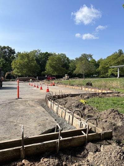 Wood curb forms with rebar dowels staged along graded parking lot edge