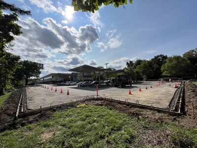 Wide view of formed curb perimeter around new lot with canopy beyond