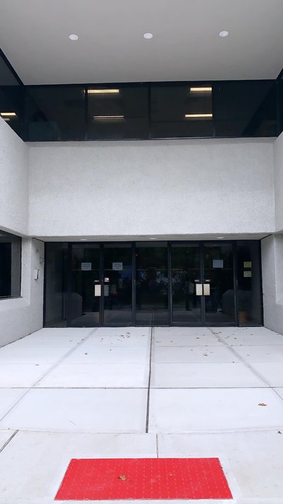 Concrete entry plaza with steps and red detectable warning pad outside commercial building entrance