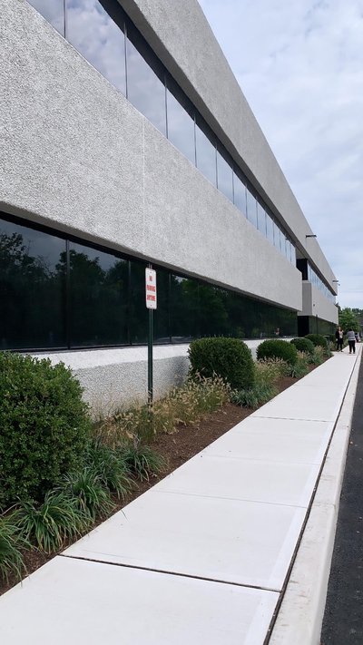 Pedestrians walking along finished concrete sidewalk beside long stucco commercial building