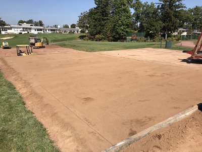 Graded sand subbase prepared for path with mini excavator on country club grounds